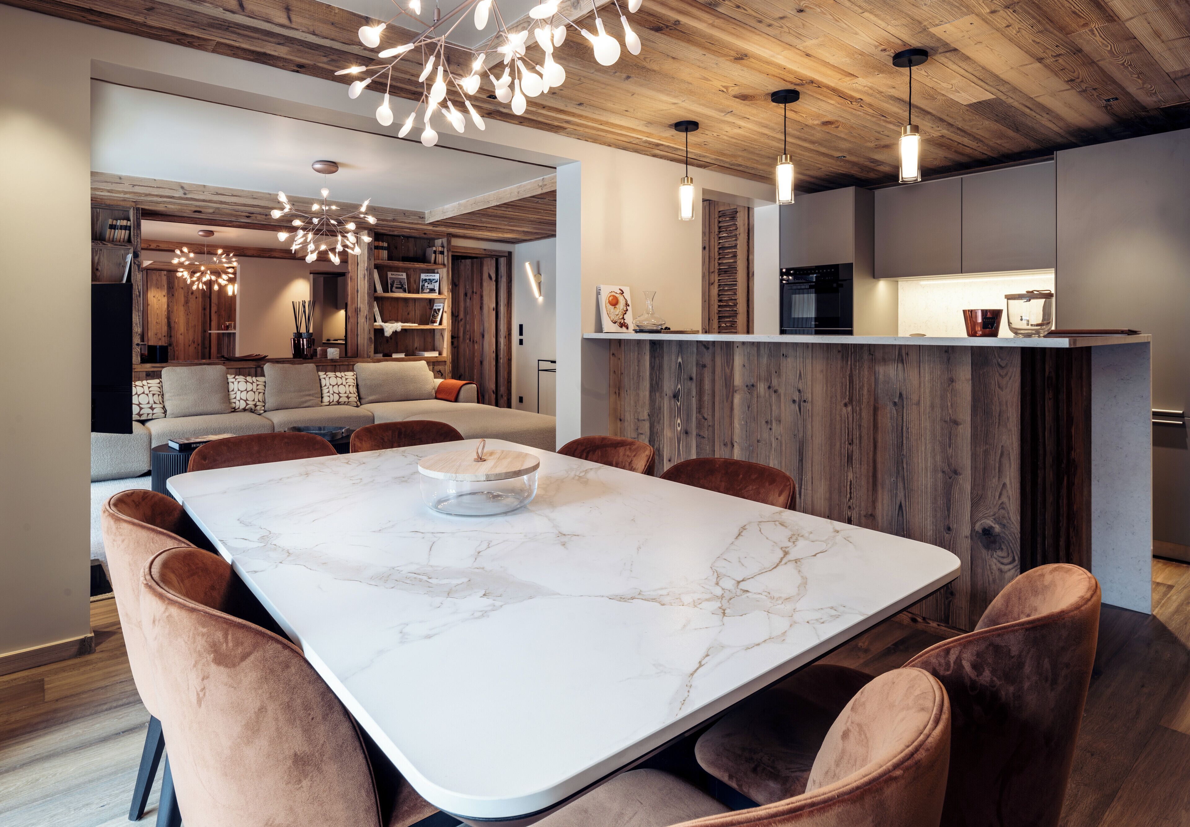 Una cocina moderna con encimera de mármol, armarios de madera e iluminación colgante.