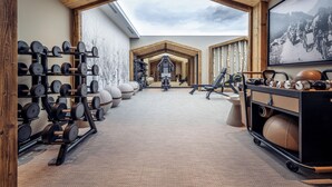 Un gimnasio con equipo de levantamiento de pesas, máquinas de ejercicio y un espejo grande.
