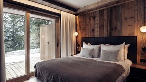 Un dormitorio con una cama grande, paneles de madera en las paredes y un ventanal corredero que da a un espacio exterior.