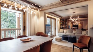 A spacious living area with a wooden ceiling, a dining table with chairs, a sofa set, and a coffee table.