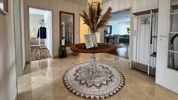 A modern living room with a round coffee table, a decorative mirror, and a hanging light fixture. - Cozy, bright vacation apartment in trendy boho style #Cosiness Company (Cuxhaven)