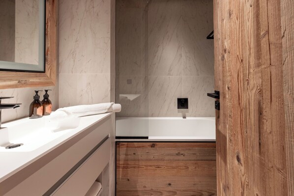 Un baño moderno con tocador de madera, un espejo grande y una bañera.