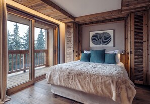 Un dormitorio con una cama grande, paredes de madera y un ventanal corredero que da a un balcón.