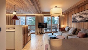 Una sala de estar acogedora con techo de madera, televisor, sofá y comedor con mesa y sillas.