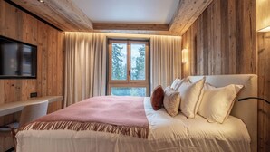 Un dormitorio con una cama grande, un escritorio y un televisor fijado a la pared.