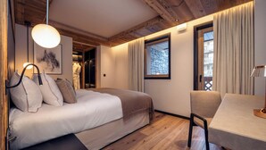 Un dormitorio con cama, mesita de noche, silla y ventana con cortinas.