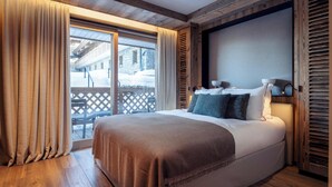Un dormitorio acogedor con una cama grande, paredes de madera y vistas a un paisaje nevado.