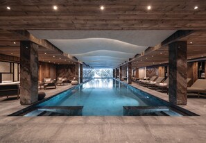 A modern indoor pool with a clear view of the outdoors, wooden ceiling beams, and lounge areas with seating. - Antarès URSA 203 -   luxury apartment ski in/ski out (Les Allues)