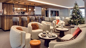 A modern lounge area with plush seating, a bar, and a decorated Christmas tree.