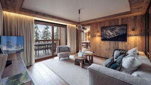 A cozy living room with a sofa, armchair, and coffee table. A large window offers a view of the outdoors.