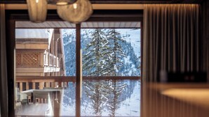 A room with a large window reflecting a snowy landscape and a building with traditional architecture.