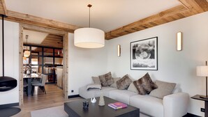 Una sala de estar moderna con sofá, mesa de centro y un comedor al fondo.