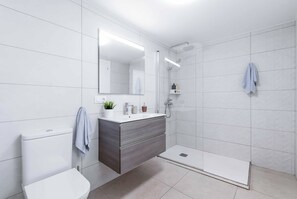 Un bany modern amb vàter, tocador i dutxa.