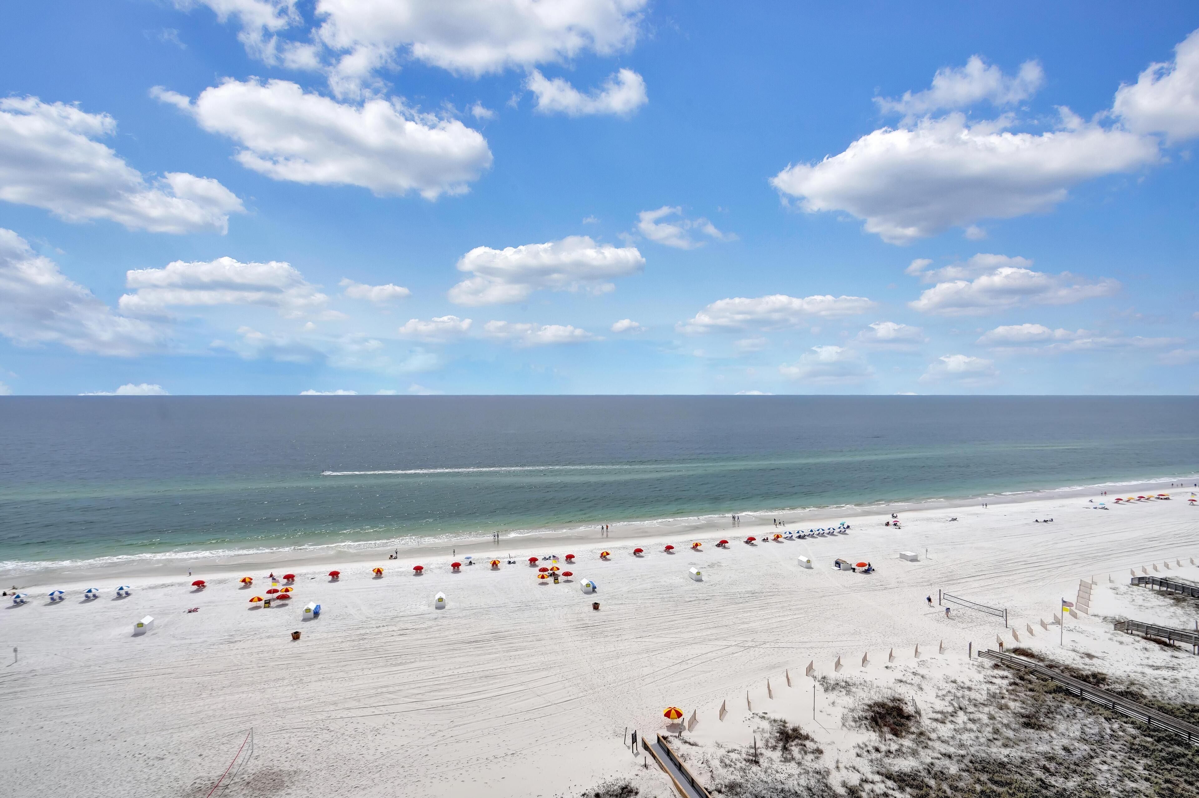 A beach with umbrellas and beachgoers.