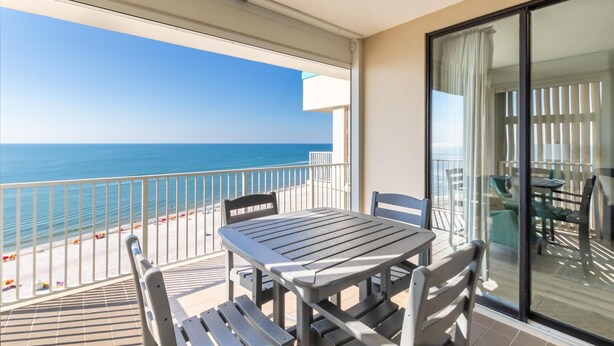 A balcony with a table and chairs, overlooking a beach and the ocean. - Shoalwater 1202 (Orange Beach)