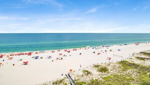 Une plage de sable blanc, avec une eau d’un bleu limpide et une promenade en bois.