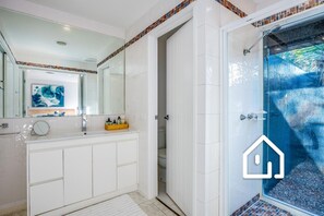 Bathroom features a large mirror, a vanity with a sink, and a shower with a glass door and outdoor view.