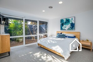 Enjoy a peaceful retreat with a garden view from the large window, a comfortable bed, and a stylish dresser.
