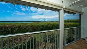 Un balcón con vistas a un campo y una construcción distante.