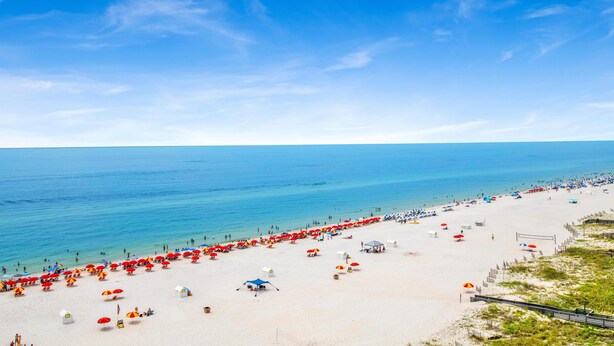 A beach with numerous umbrellas and beachgoers. - Windward Pointe 1002 (Orange Beach)