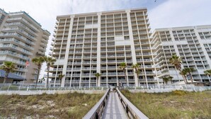 A multi-story hotel with a central atrium, balconies, and a pathway leading to the entrance. - Windward Pointe 1002 (Orange Beach)