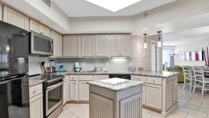 A modern kitchen with a central island, stainless steel appliances, and light-colored cabinetry. - Windward Pointe 1002 (Orange Beach)