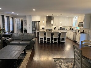A modern kitchen with white cabinets, stainless steel appliances, and a central island with bar stools.