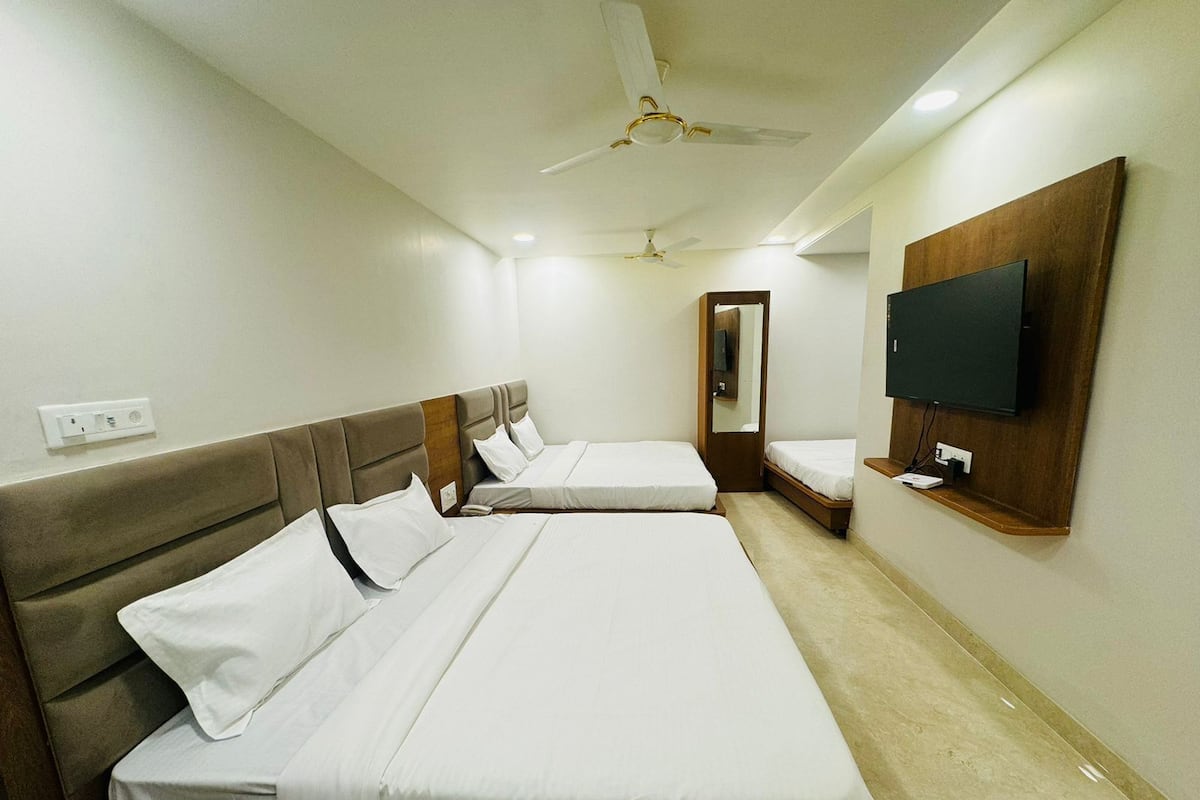 Une chambre d’hôtel avec deux lits, un ventilateur de plafond, un téléviseur fixé au mur et un miroir.