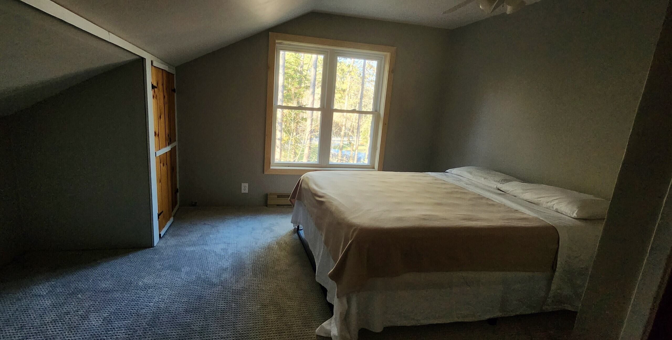 Ein Schlafzimmer mit einem Einzelbett, einem Fenster und einer Schräge.