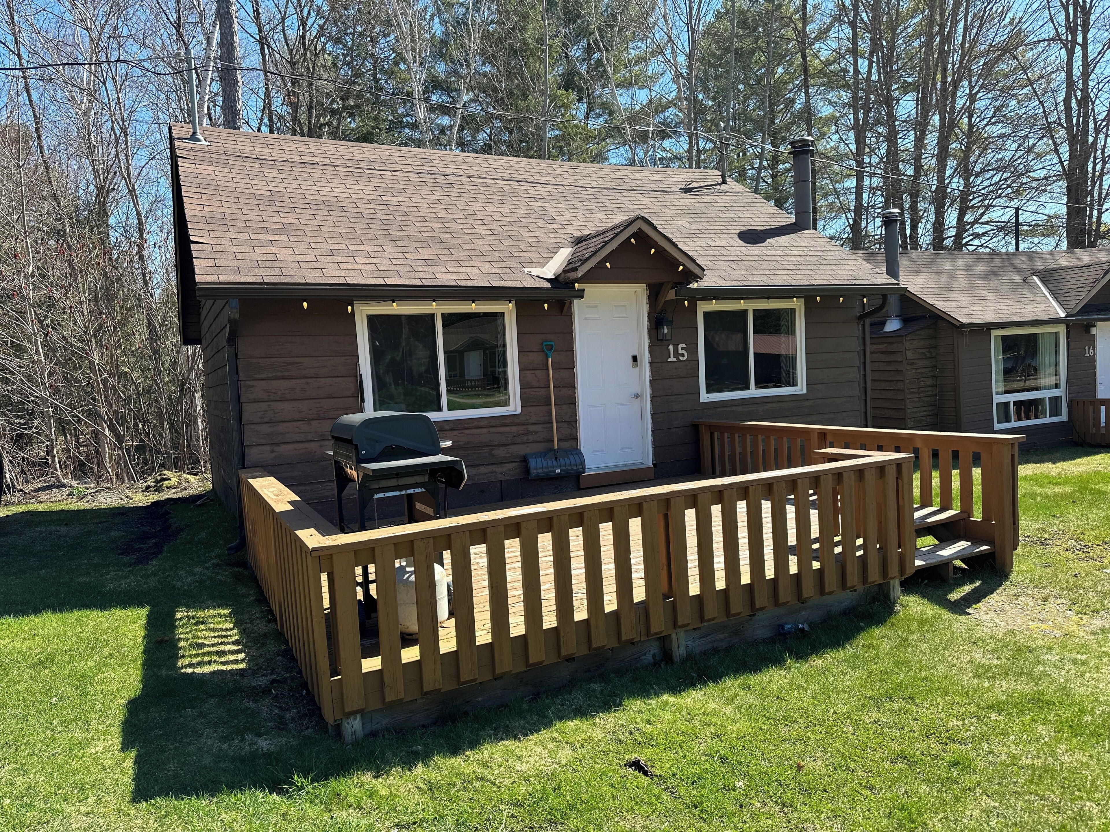A cabin with a deck, a grill, and a door marked with the number 15.