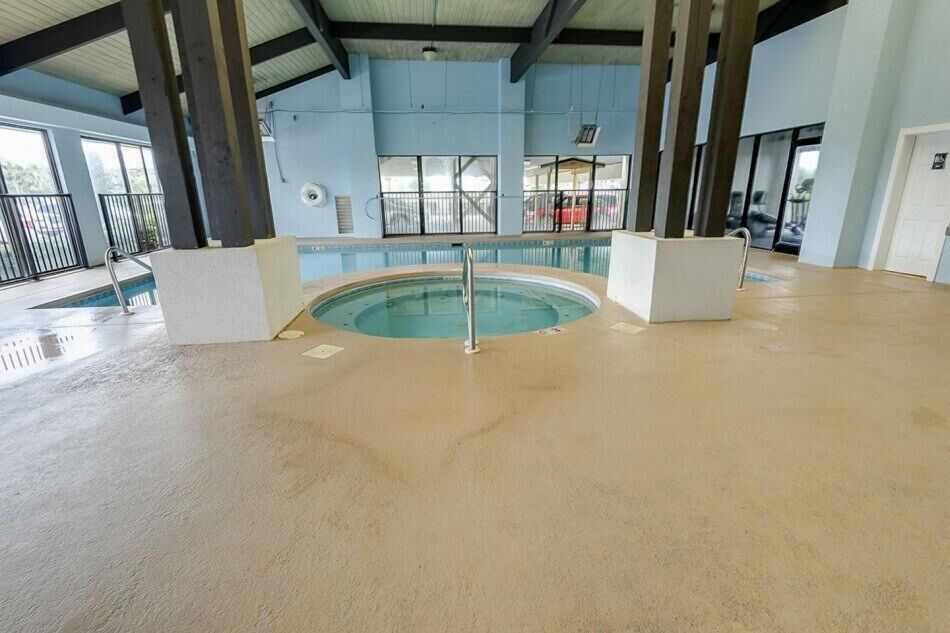 An indoor swimming pool with a clear view of the surrounding area, including windows and a balcony.
