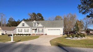 A two-story house with a garage, a driveway, and a well-maintained lawn.