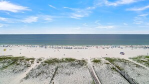 A beach with a sandy shore, a wooden boardwalk, and a clear blue sky. - Tropic Isles 801 (Gulf Shores)