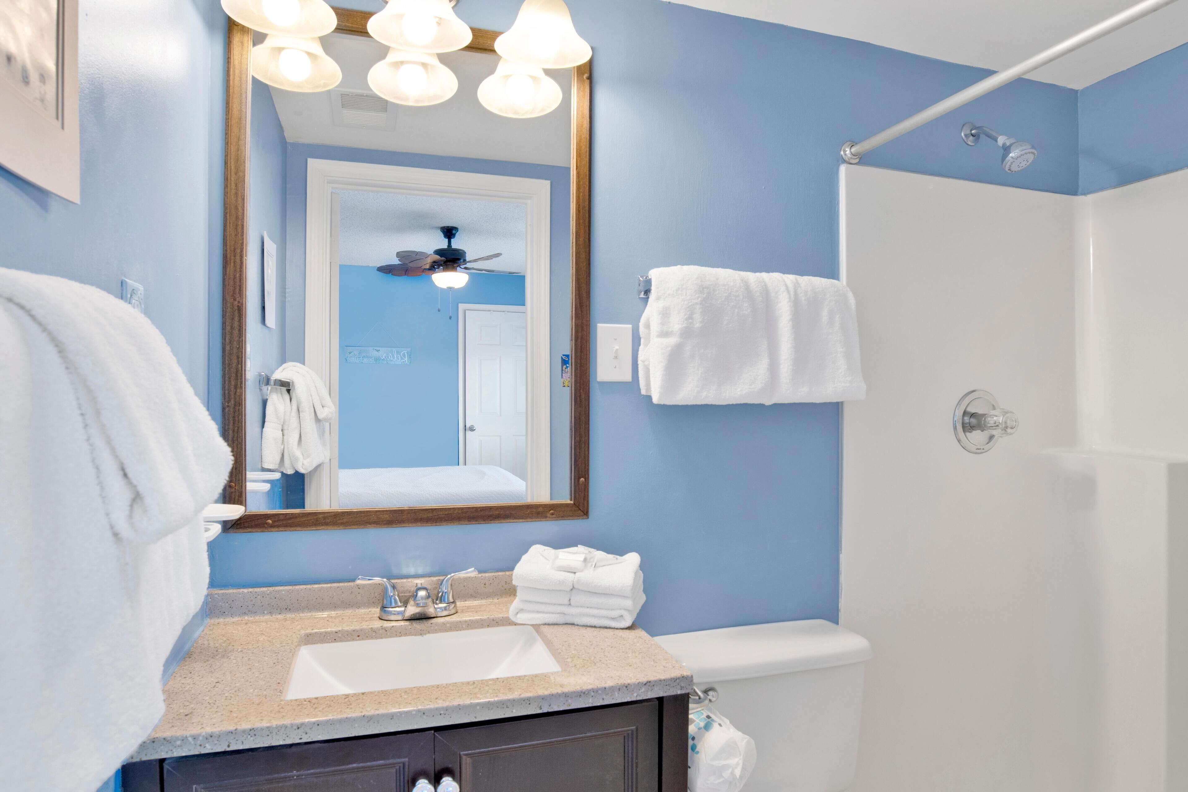 A bathroom with a sink, mirror, and shower.