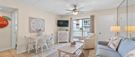 A living room with a sofa, coffee table, TV, and a balcony view.