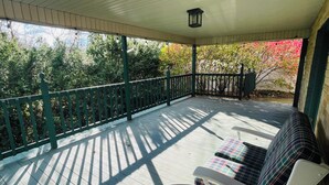 A covered porch with a wooden floor, a green railing, and a bench with plaid cushions. - Near Canton 3-bedroom house in  Louisville with WiFi, patio  (Louisville)