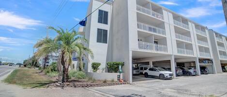 A multi-story parking garage attached to a white building with balconies.