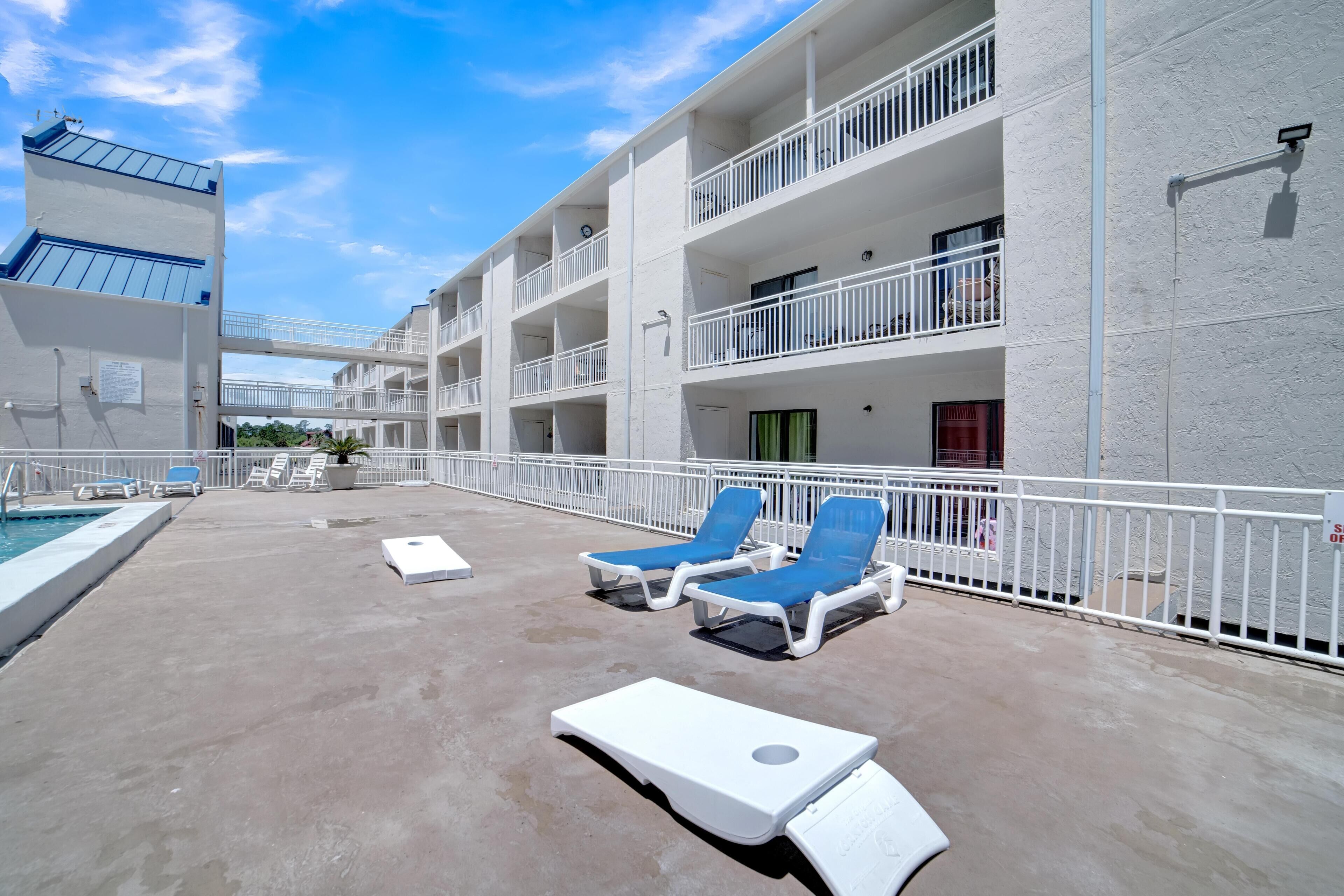 Un hôtel à plusieurs étages doté de balcons, d’une piscine et de chaises longues.