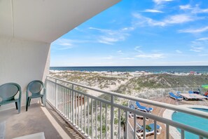 Ein Balkon mit Blick auf den Strand, Liegestühle und ein Pool.