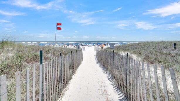A sandy beach path leading to the ocean with a flag on the left. - Sugar Beach 230 (Orange Beach)