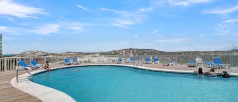 A pool with blue chairs and a wooden deck.