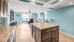 A spacious kitchen with a granite countertop, dark wooden cabinets, and a ceiling fan. - Sugar Beach 241 (Orange Beach)