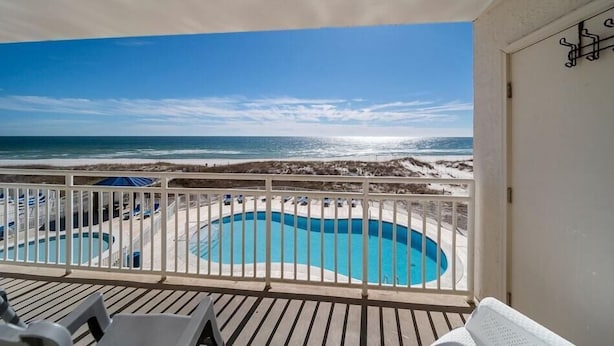 A balcony with a view of a beach and a swimming pool. - Sugar Beach 245 (Orange Beach)