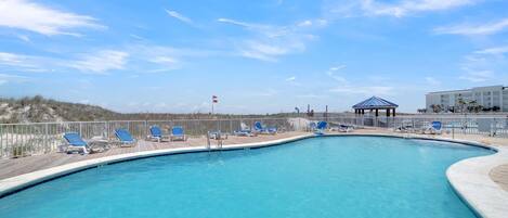 A swimming pool with blue lounge chairs and a gazebo.