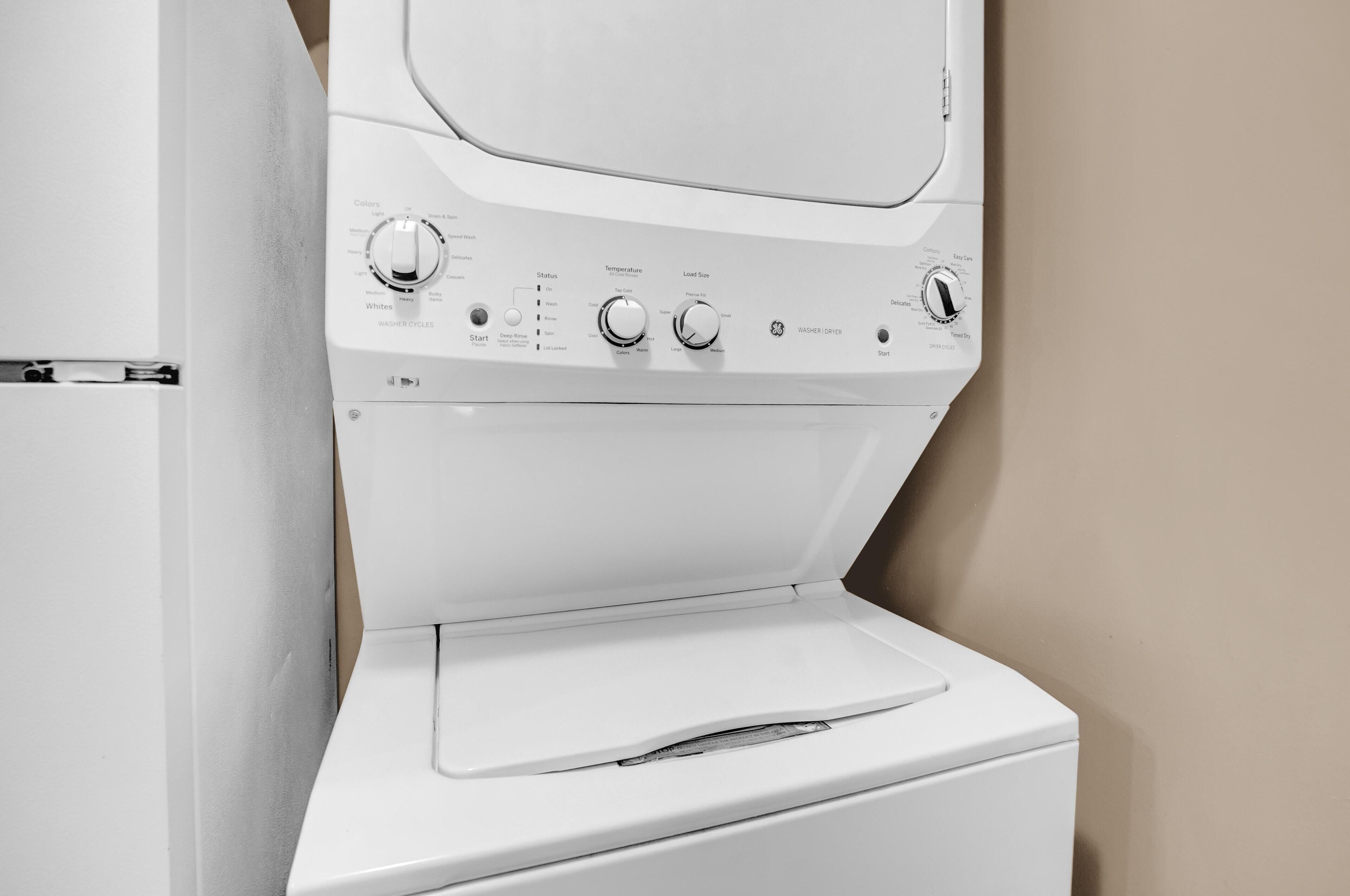 Vue de face d’un appareil combiné lave-linge et sèche-linge blanc, avec ses boutons de commande et sa porte.