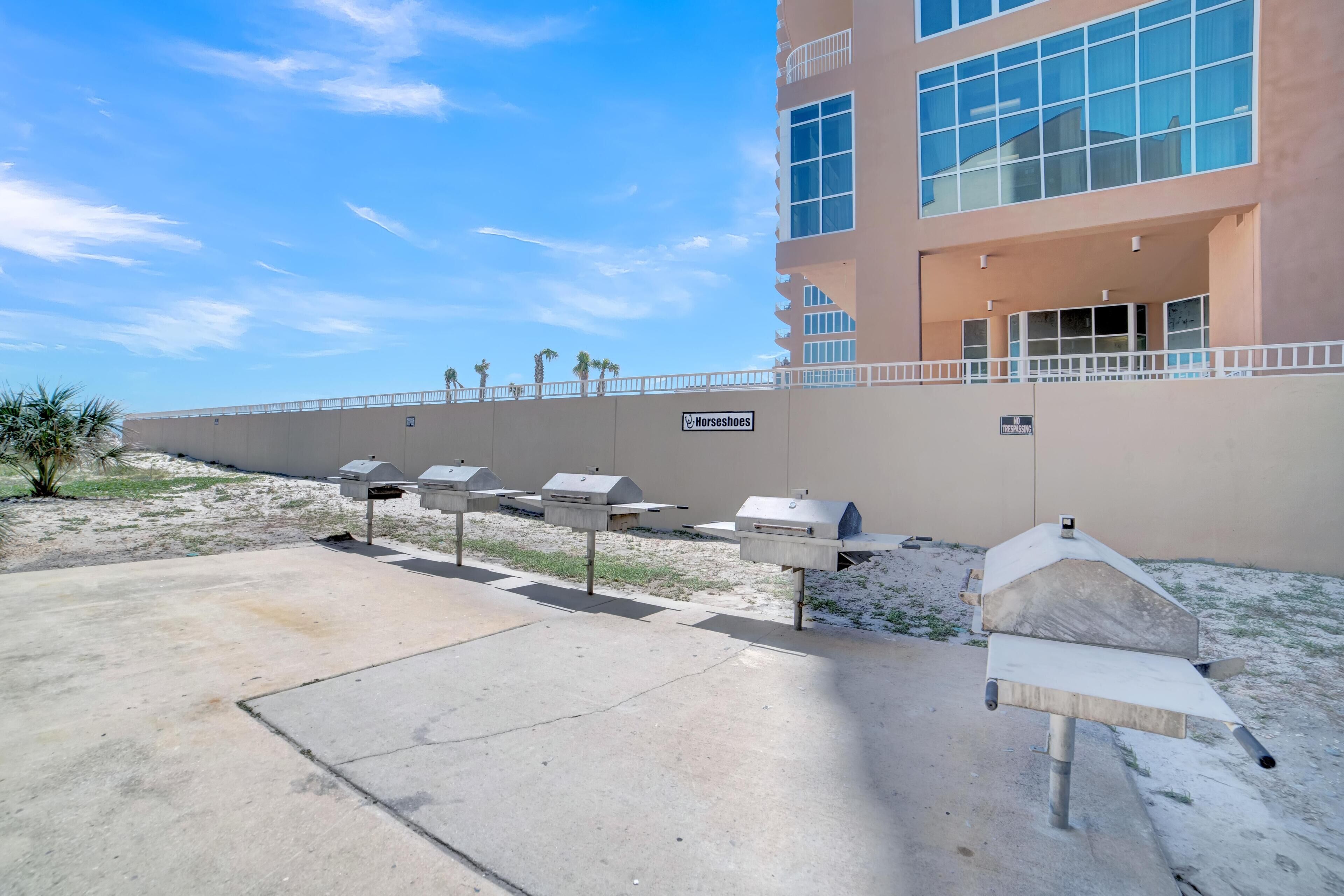 Outdoor barbecue grills, a building with large windows, and a clear sky.