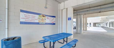 A parking garage with a picnic table and a trash bin.