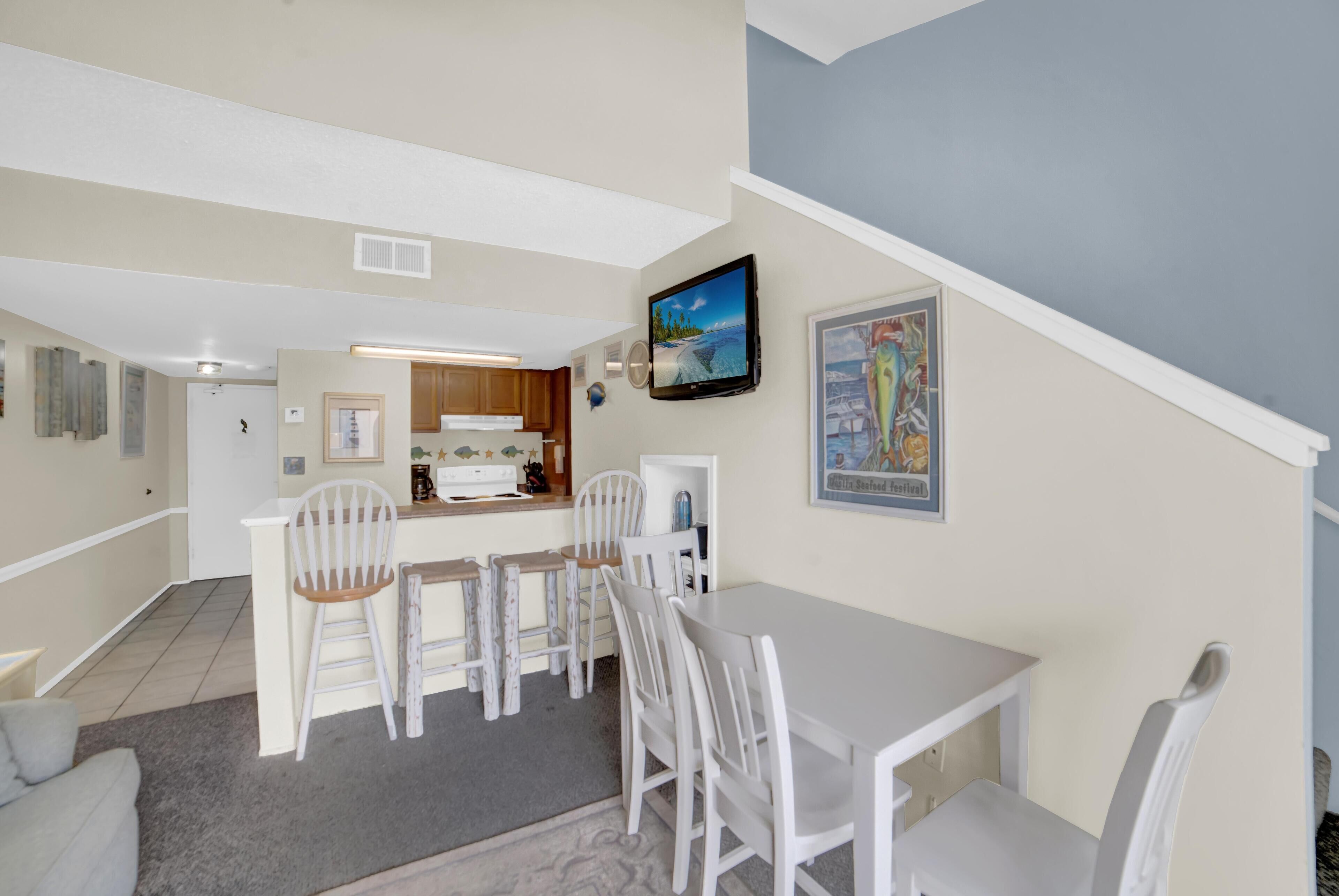A compact living space with a dining area, kitchen, and a staircase leading to an upper level.