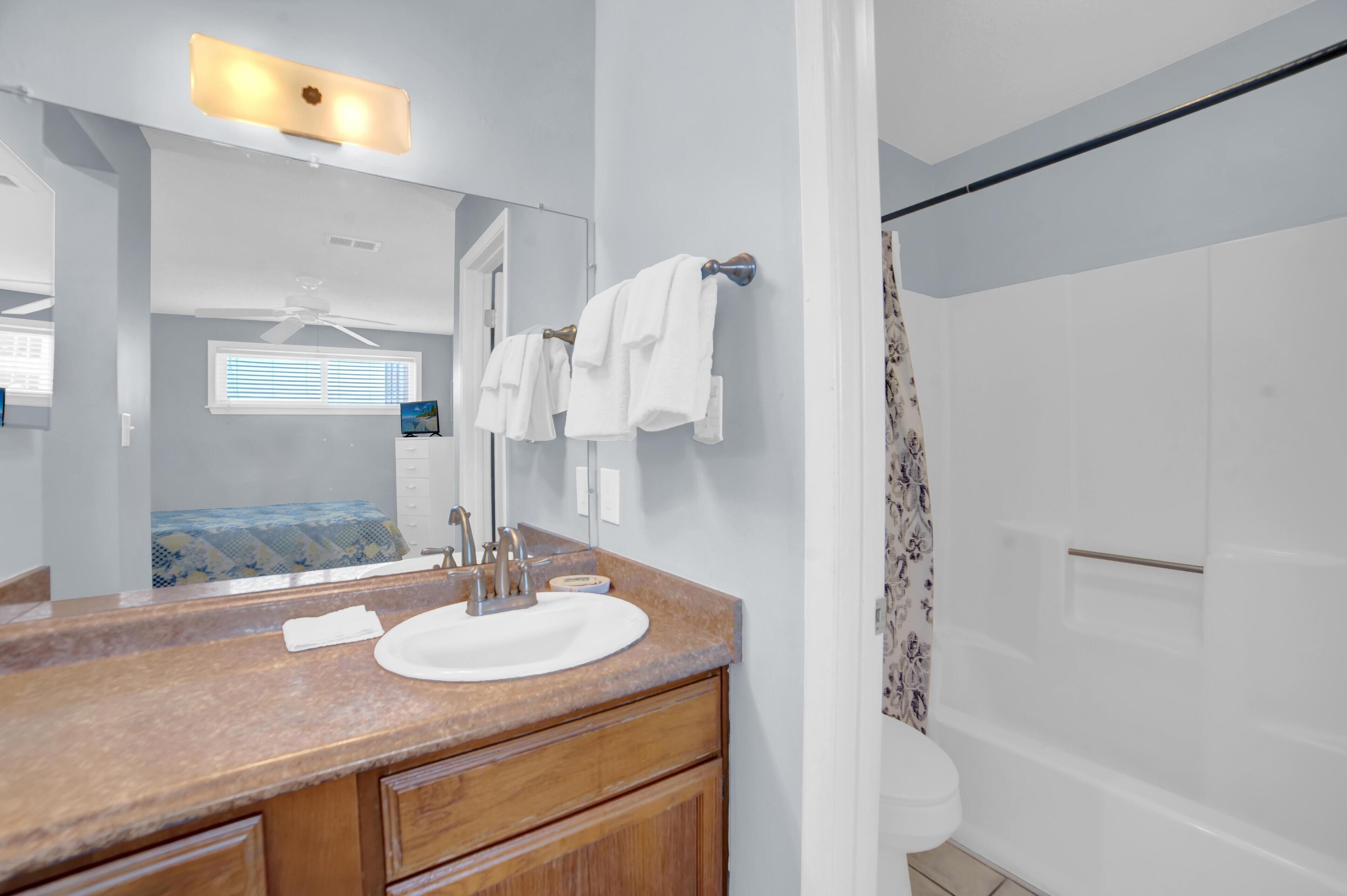 A modern bathroom with a white sink, wooden vanity, and a large mirror.