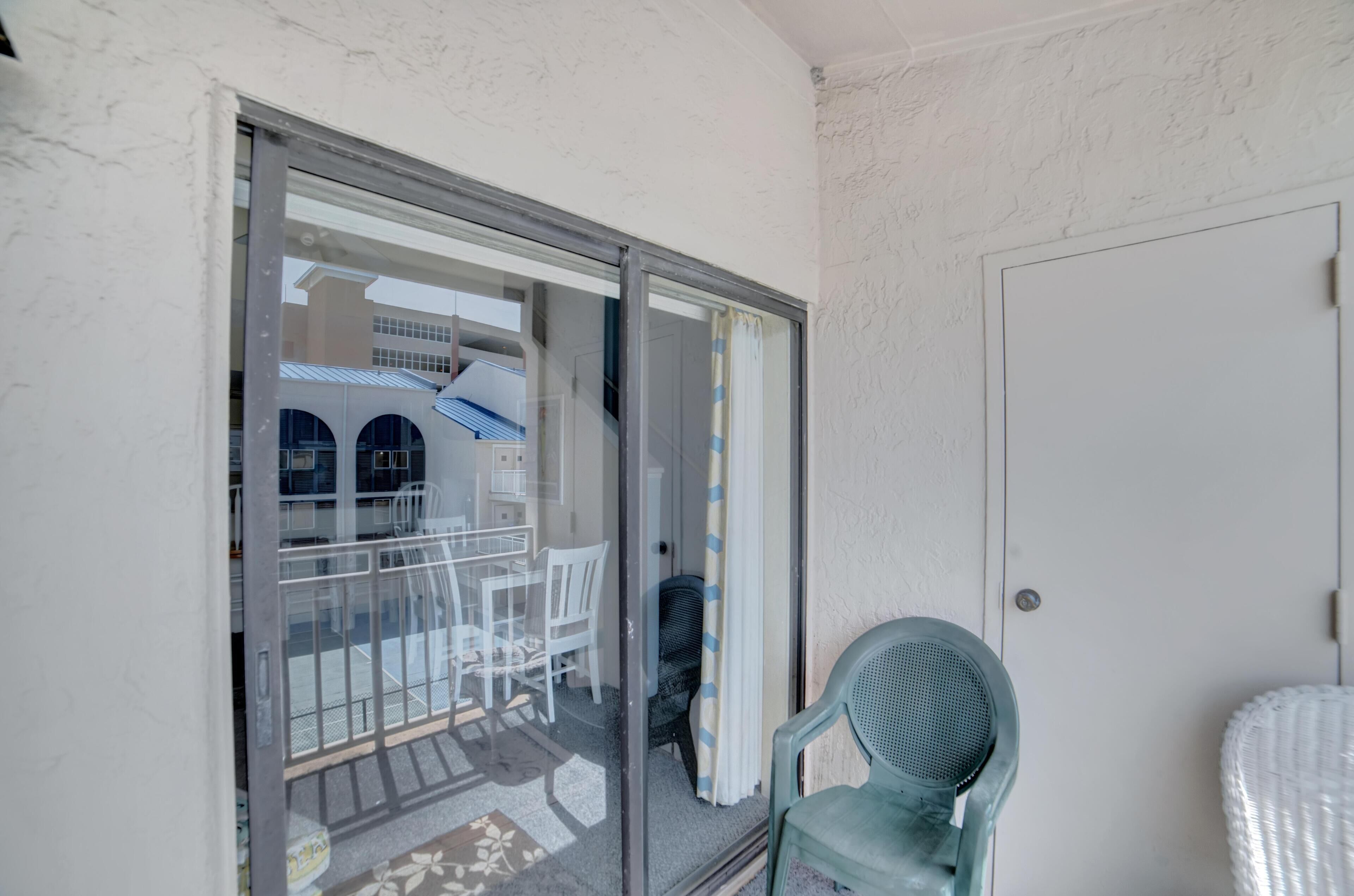 A balcony with a glass door leading to an outdoor area with a table and chairs.